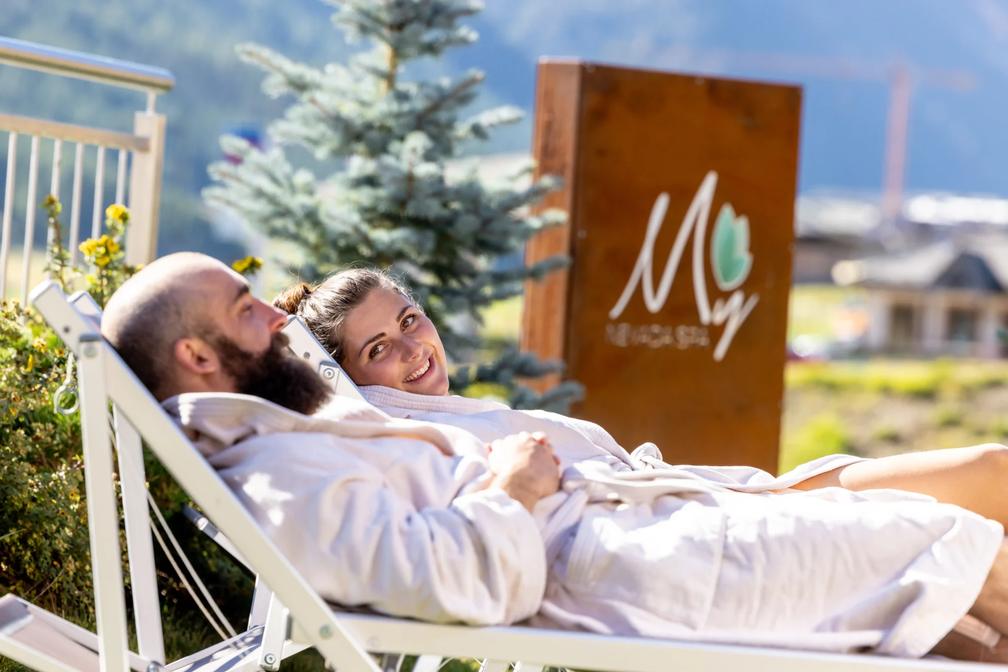Coppia in accappatoio rilassata su lettini all'aperto vicino alla spa dell'hotel a Livigno