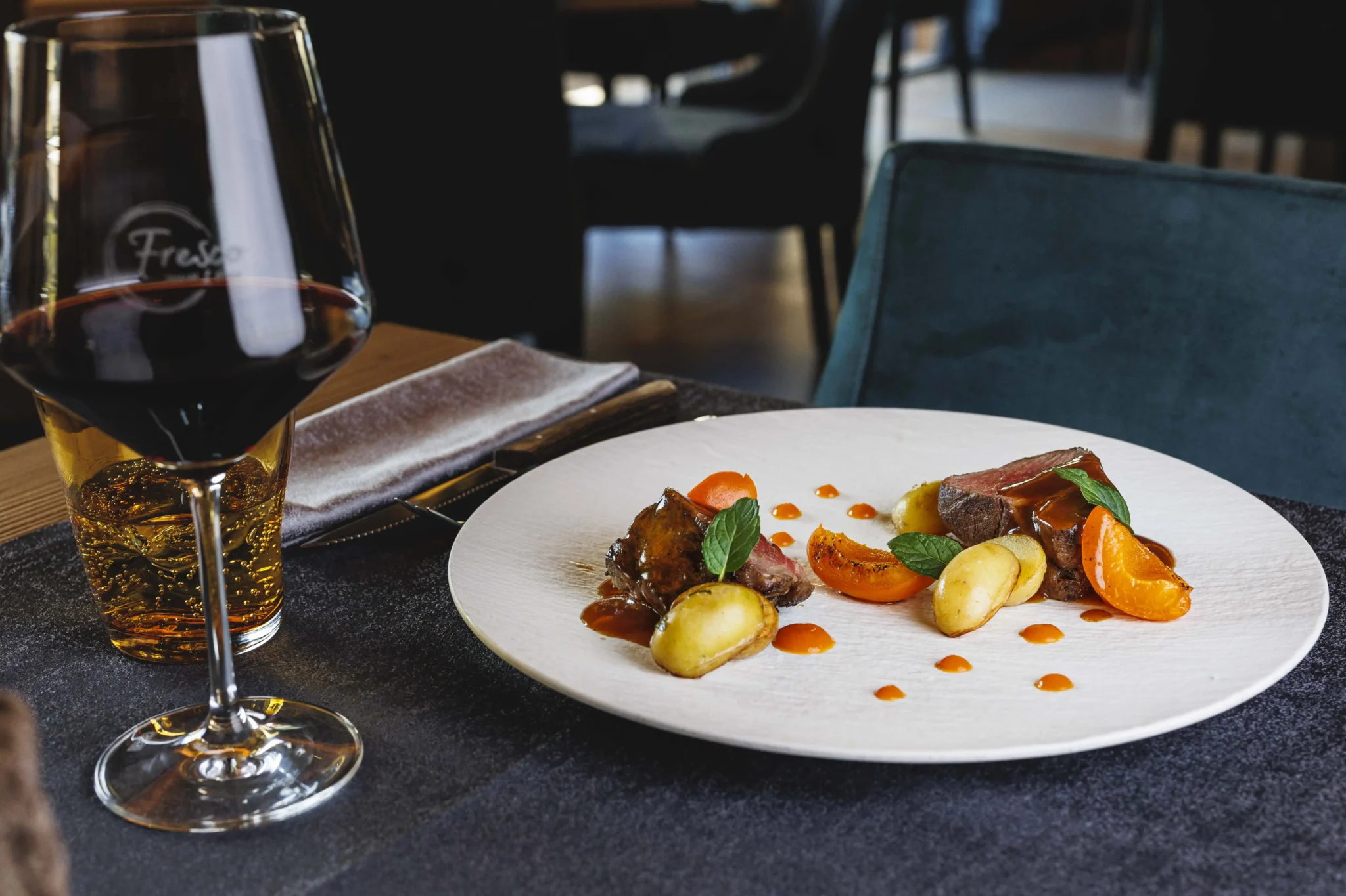 Piatto gourmet con carne e verdure accompagnato da un calice di vino nel ristorante dell'hotel a Livigno
