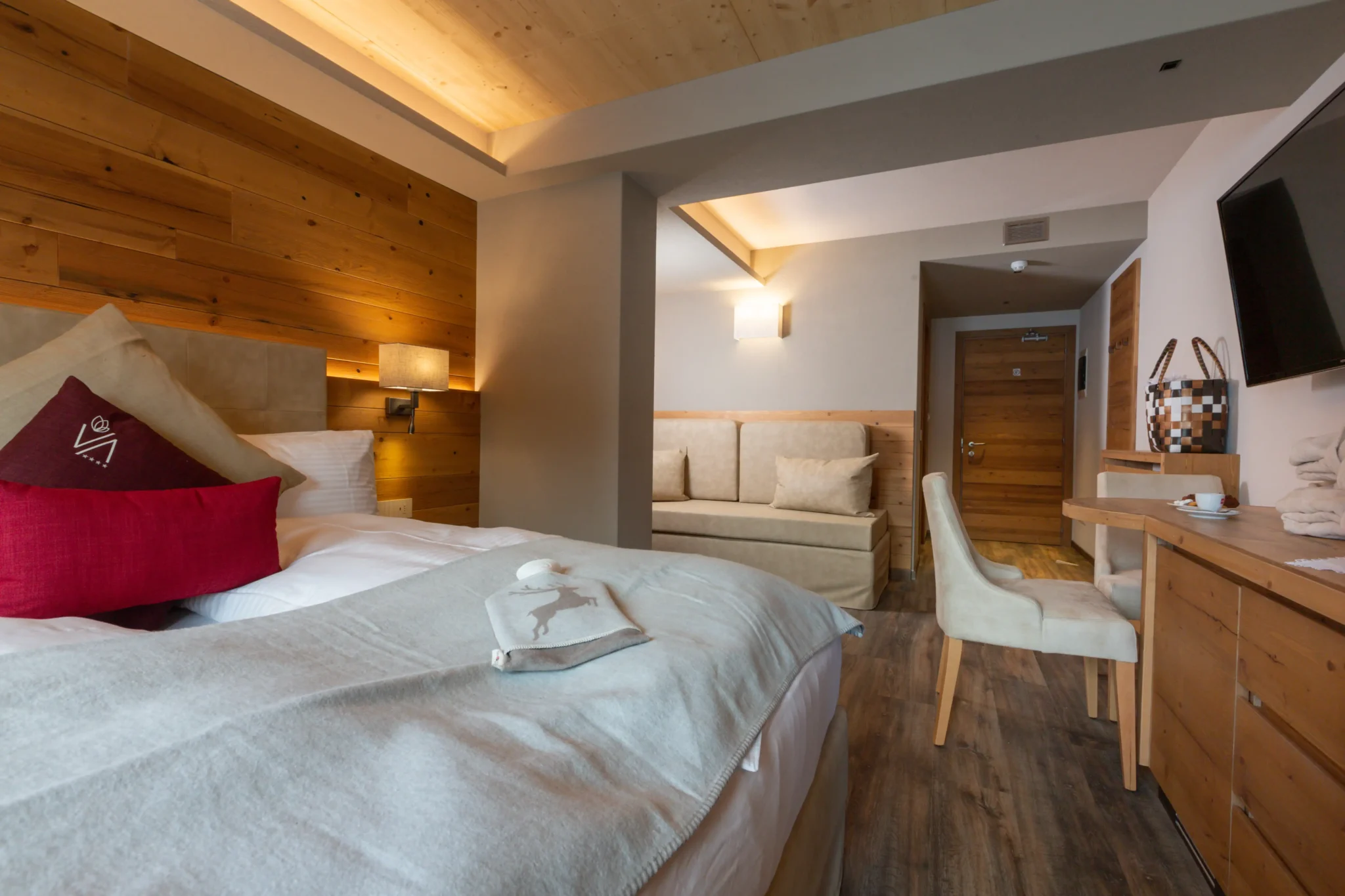 Camera d'hotel elegante con letto matrimoniale, divano e arredi in legno a Livigno