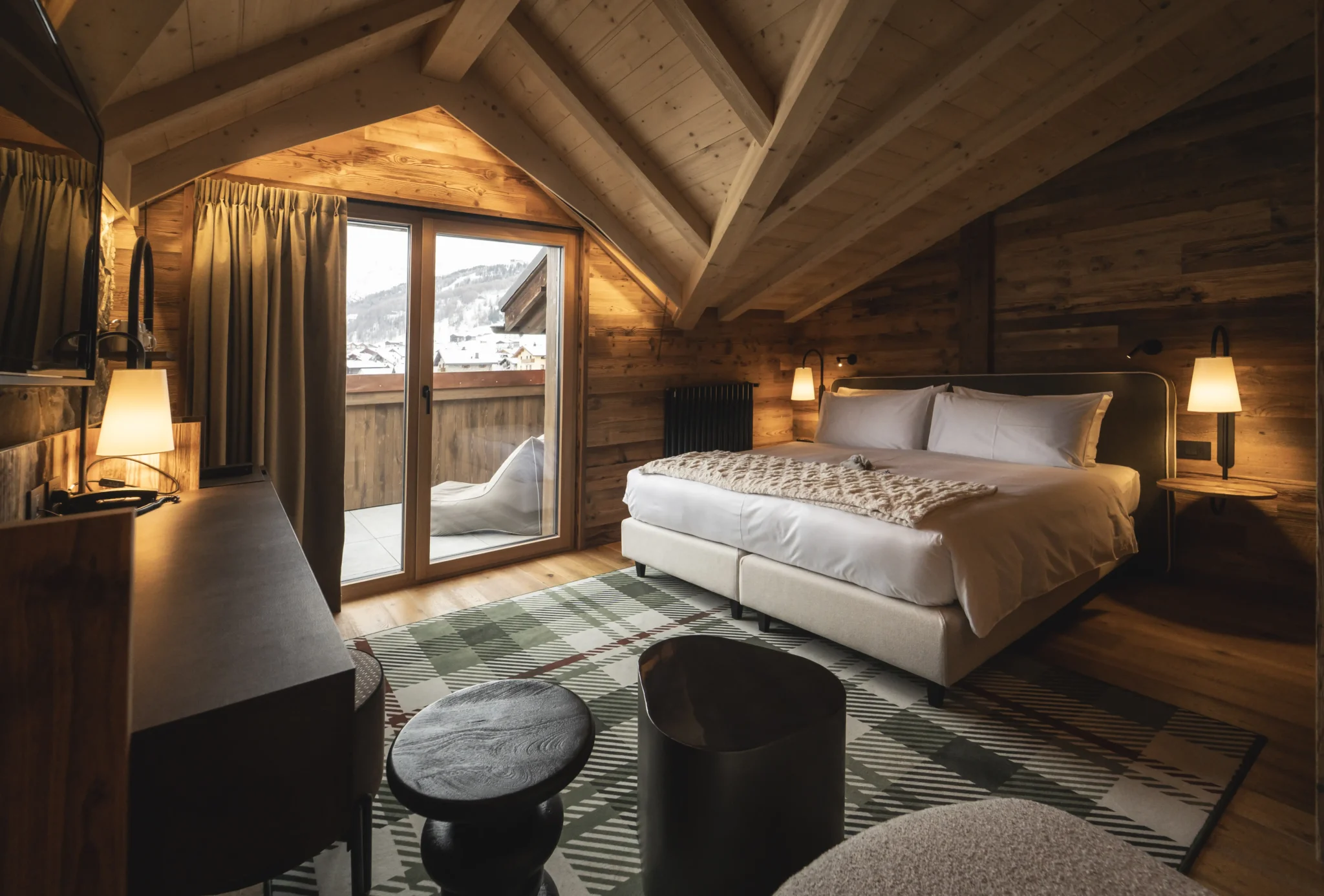 Camera in stile chalet con soffitto in legno, letto matrimoniale e balcone affacciato sulle Alpi a Livigno