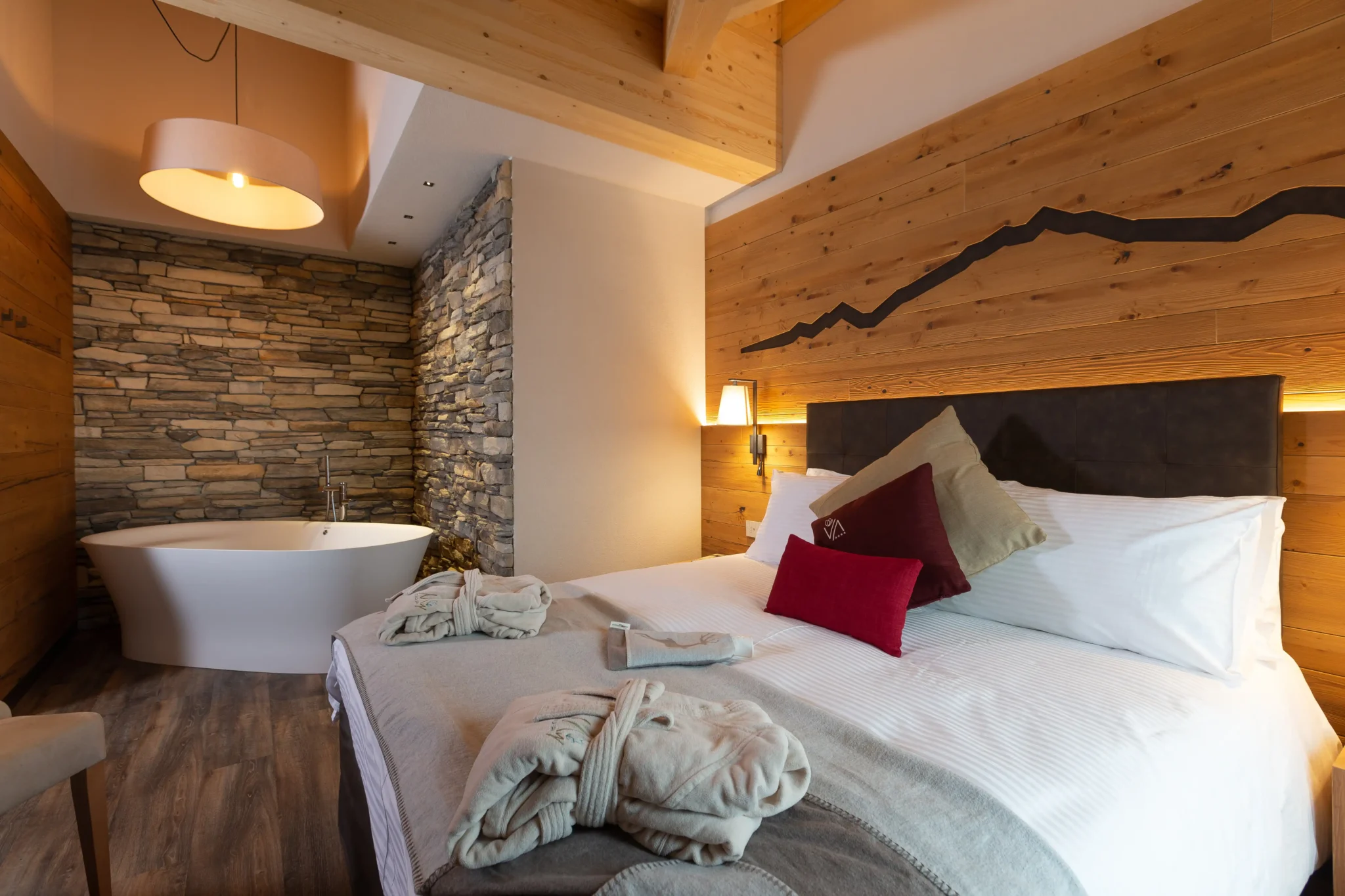 Camera hotel con vasca da bagno in pietra e letto matrimoniale accogliente in legno a Livigno