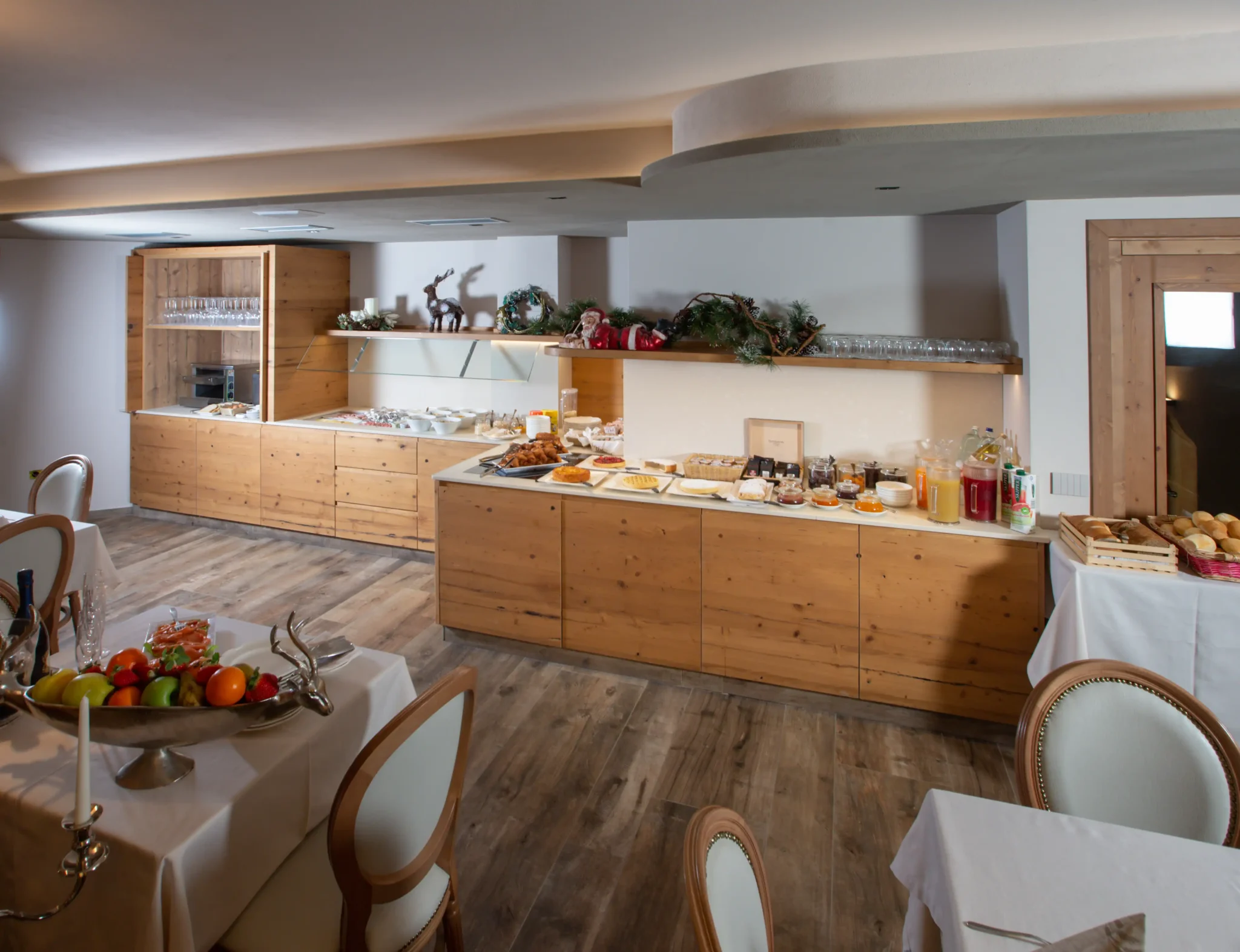 Sala colazione con buffet in legno, decorazioni natalizie e tavoli apparecchiati con eleganza