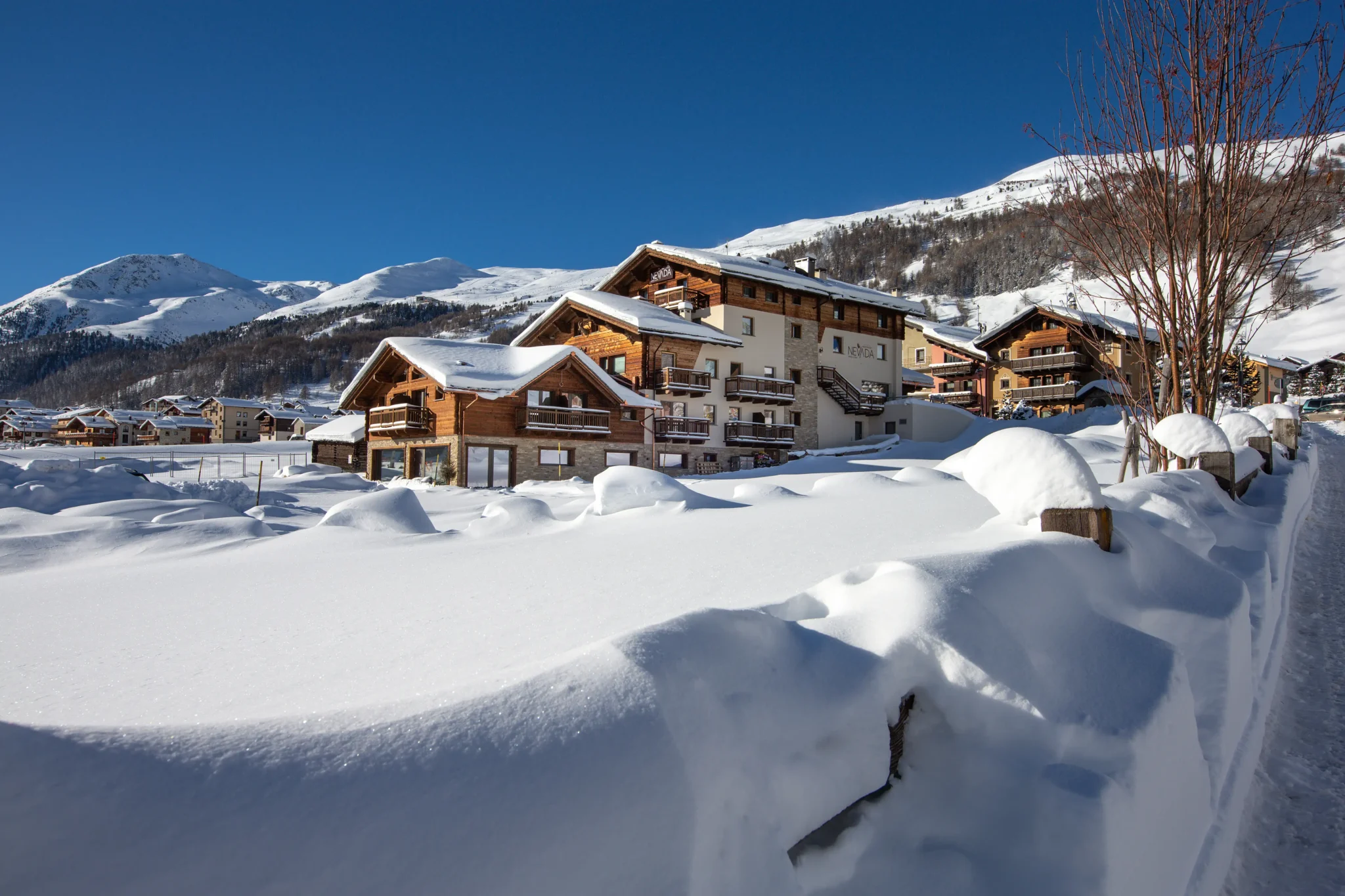Hotel di montagna con facciate in legno immerso nella neve, circondato da vette innevate a Livigno