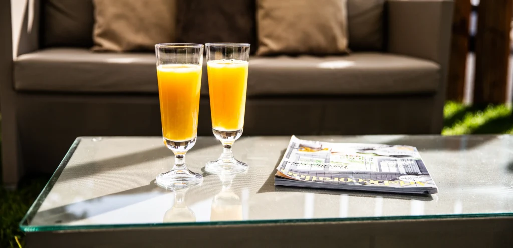 Due bicchieri di succo d'arancia su tavolino in vetro accanto a un divano, atmosfera rilassante