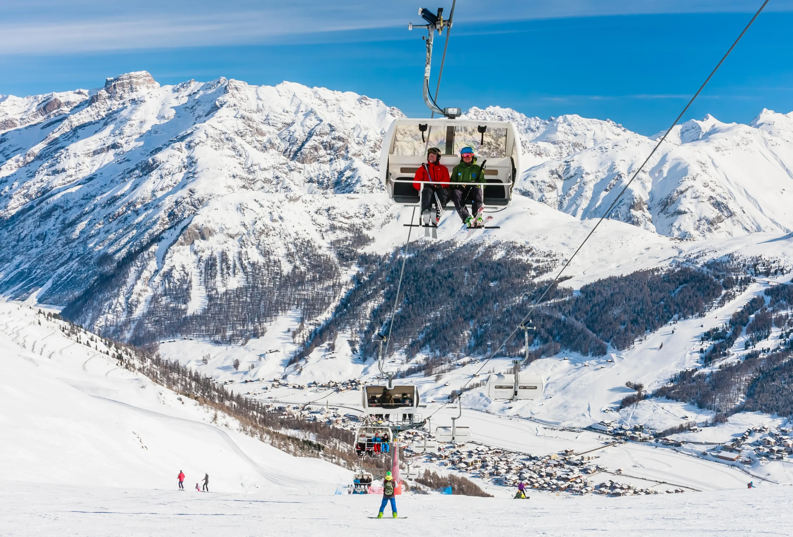 Coppia in seggiovia panoramica sulle piste innevate di Livigno con montagne alpine