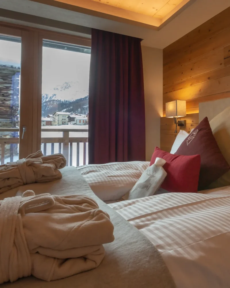Camera d'albergo con vista sulle montagne di Livigno, accappatoi soffici e cuscini decorativi
