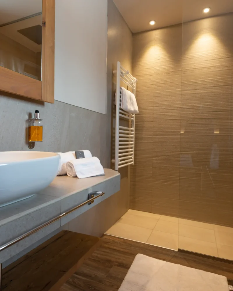 Bagno elegante con lavabo d'appoggio, doccia in vetro e scaldasalviette in un hotel a Livigno