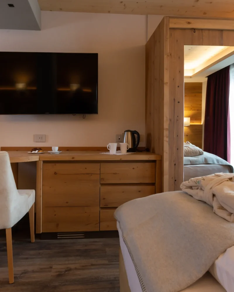 Camera d'albergo in stile montano a Livigno con letto, scrivania in legno e tv a parete