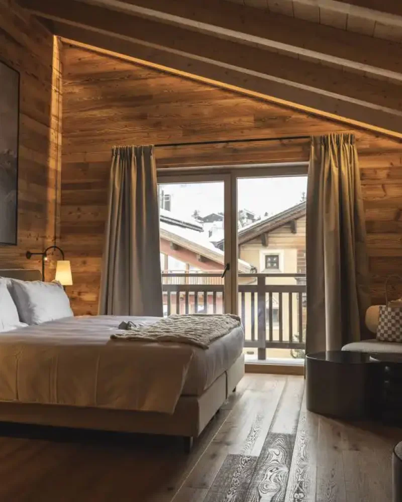 Camera in legno con letto matrimoniale, balcone panoramico e atmosfera calda tipica di Livigno