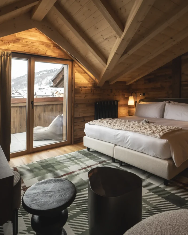 Camera in stile chalet con soffitto in legno, letto matrimoniale e balcone affacciato sulle Alpi a Livigno