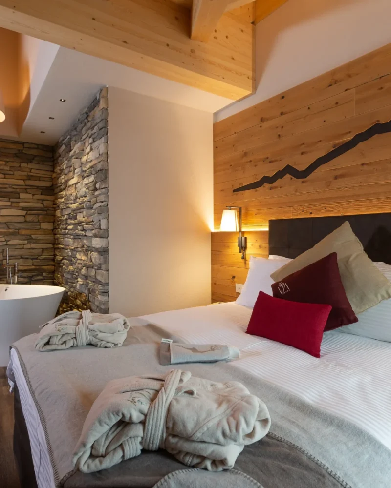 Camera hotel con vasca da bagno in pietra e letto matrimoniale accogliente in legno a Livigno