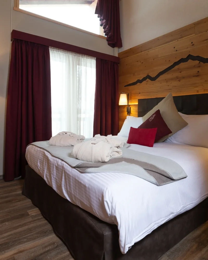 Camera doppia romantica con letto in legno, decorazione montagne e lampada da terra