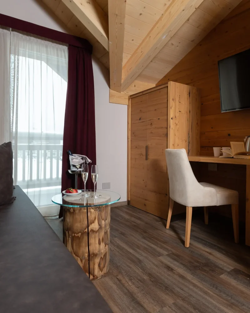 Camera in stile chalet con divano patchwork, scrivania in legno e vista sulle montagne di Livigno