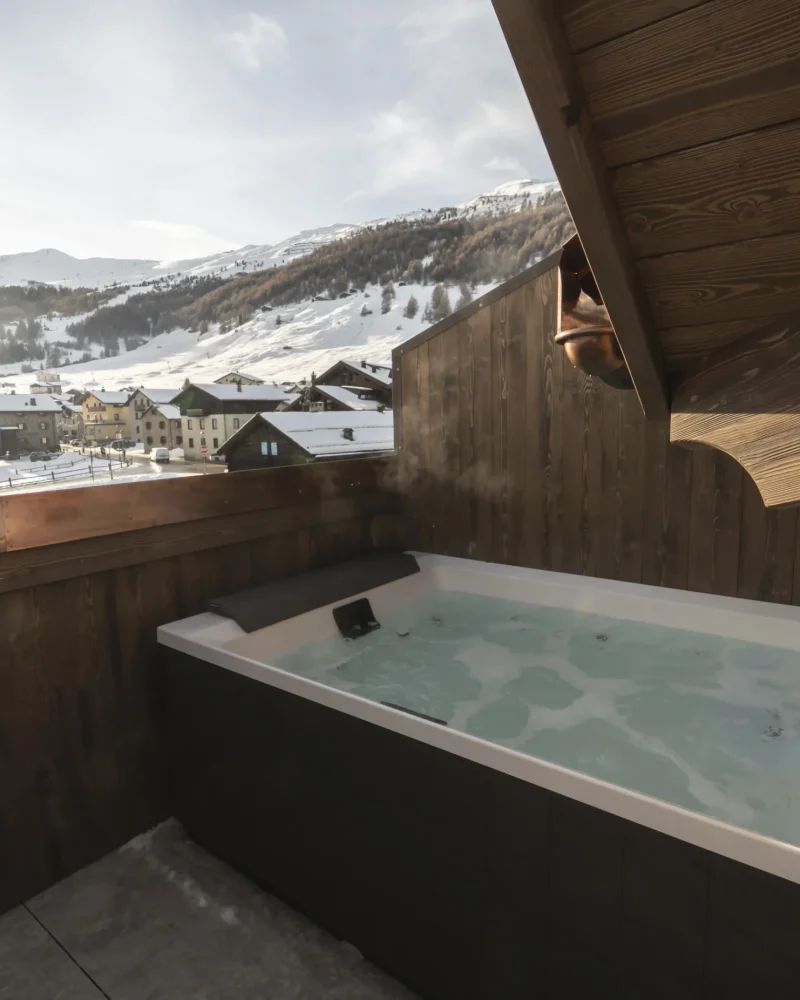 Vasca idromassaggio privata sul terrazzo in legno con vista sulle montagne innevate di Livigno